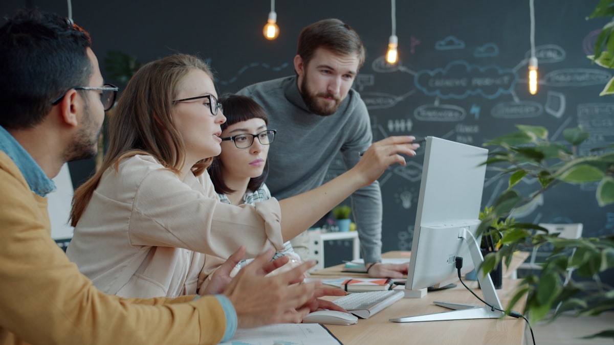 A small engineering team collaborating around a laptop in an open office — the kind of embedded context where a fractional CTO operates