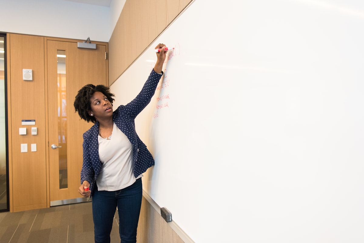 A technical leader writing on a whiteboard during a working session — the architecture and planning work fractional CTOs do in practice